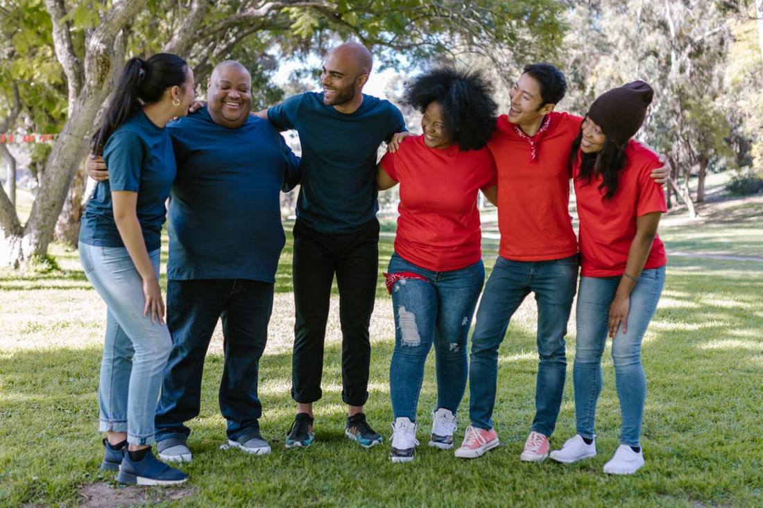 A diverse group of TAUM volunteers laughing together outdoors.