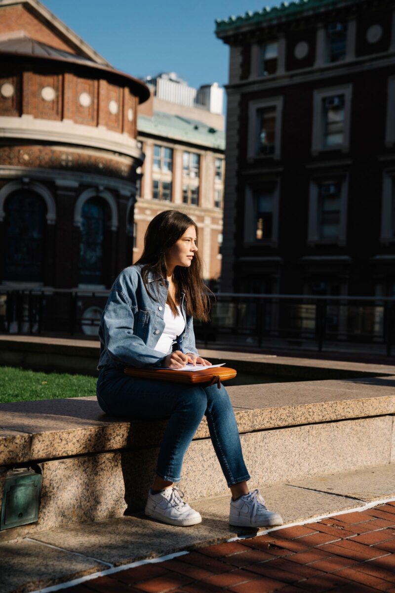 A student writing on a campus bench