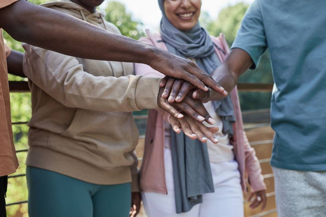 A diverse group of neighbors placing their hands together in a gesture of unity.