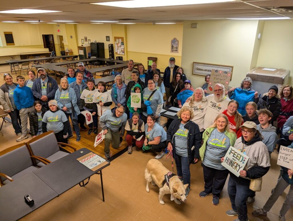 A large group of walkers with handmade signs gathered for the CROP Hunger Walk.