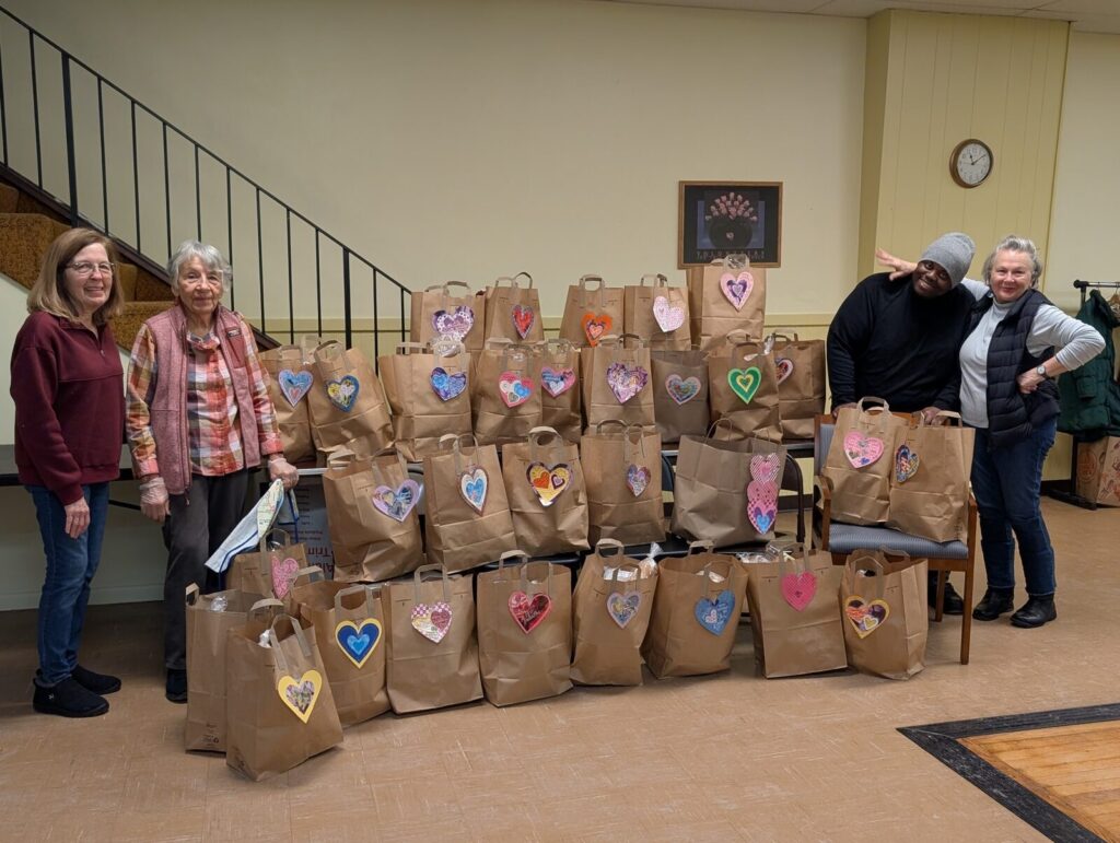 Rows of paper grocery bags decorated with hand-drawn hearts, ready to go out.
