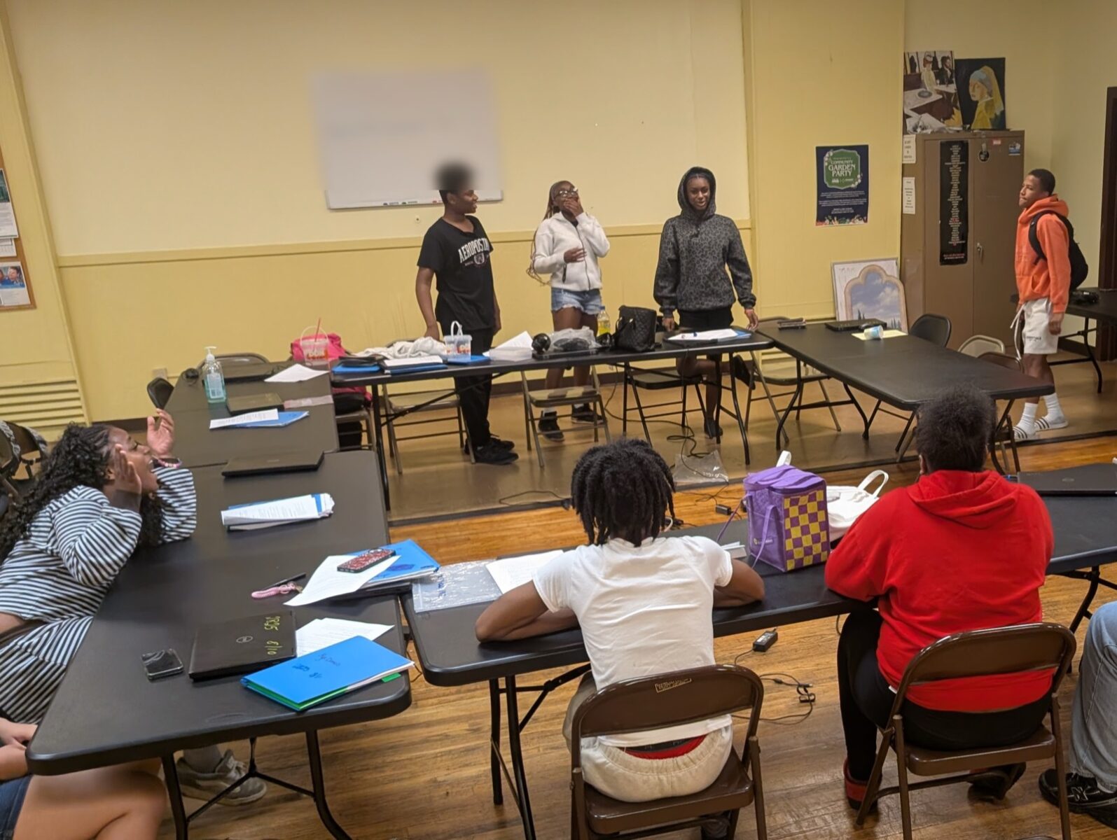 Three teens presenting to the room at the Teen Tech Center while the rest of the group listens.